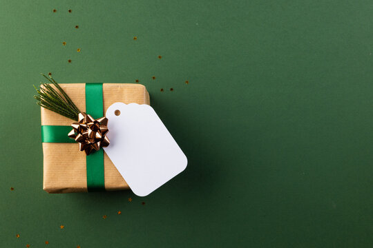 Christmas presents with green ribbon and tag with copy space on green background