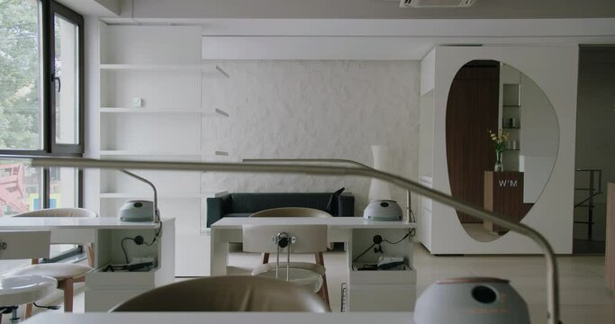 Modern interior in nail salon, chairs and table with lamp. Empty workplaces at beauty studio with furniture and professional equipment