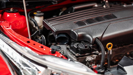 New modern car engine under the hood of red car in auto repair garage. Mechanical engineering and...