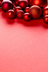 Vertical image of christmas red baubles decorations with copy space on red background