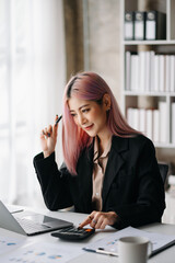 Asian Businesswoman Analyzing Finance on Tablet and Laptop at modern Office Desk tax, report, accounting, statistics, and analytical research concept.