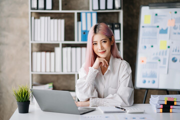 Asian Businesswoman Analyzing Finance on Tablet and Laptop at modern Office Desk tax, report, accounting, statistics, and analytical research concept.