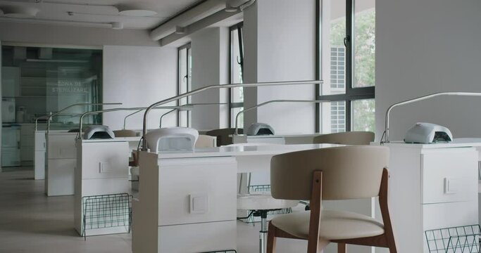 Comfort workplaces with tables, chairs and professional equipment in nail studio. Beauty salon with modern interior and stylish furniture.