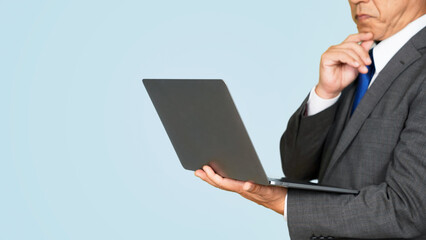 ノートパソコンを見ながら考えるビジネスマン