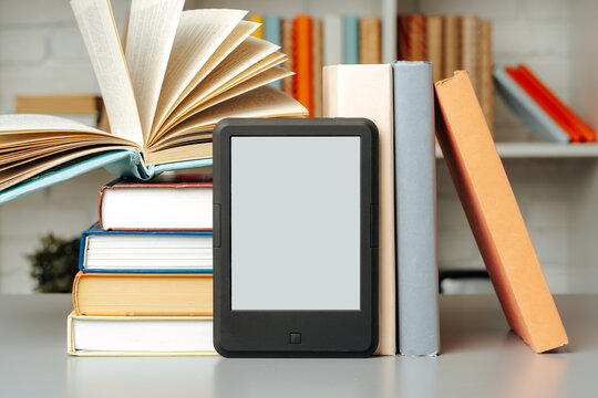 E-book reader on table against book shelves