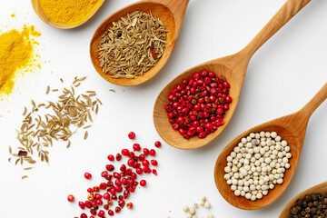 Wooden spoons with various spices isolated on white background