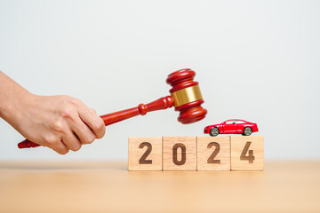 Car Law, Insurance, auto Tax, Auction and Bidding concepts. 2024 year block with crashed small toy car models with Judges gavel on desk in courthouse.