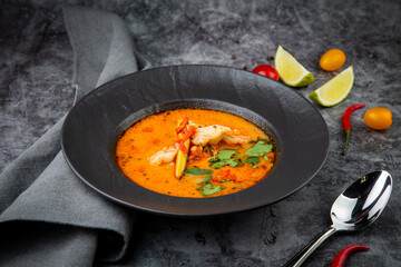 tom yam soup with chicken, lime, cherry tomatoes and parsley side view