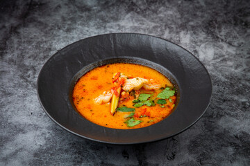 tom yam soup with chicken, lime, cherry tomatoes and parsley side view