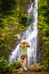 A slender girl admires a beautiful waterfall in Mtirala National Park, Georgia.