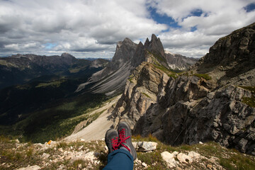 Trekking boots of a hiker while sitting on top of a mountain in Seceda, Dolomites, Italy