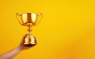 hand holding gold trophy isolated in yellow background copy space
