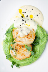 cheesecakes with creamy sauce on broccoli puree, top view