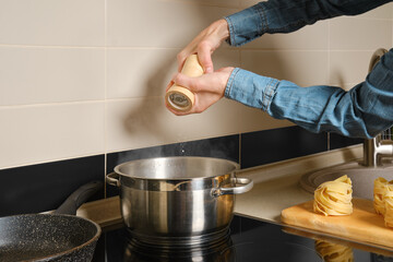 Unrecognizable woman adds salt to boiling water