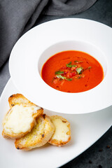 red tomato cream soup with herbs and toasted bread side view