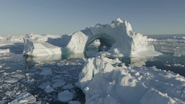 Gaint iceberg with ice cave melting in the ocean. Icebergs from melting glacier float in Disco Bay, near Ilulissat, Greenland. Aerial shot, climate change concept
