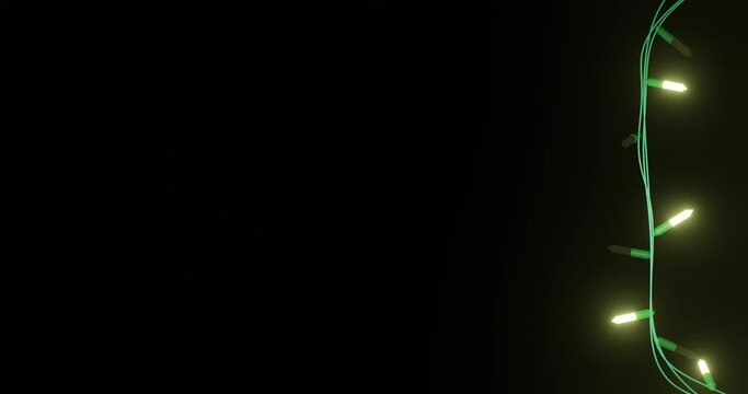 Strand of yellow christmas string lights flashing on black background, copy space