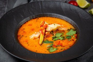 tom yam soup with chicken, lime, cherry tomatoes and parsley side view