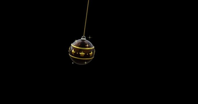 Swinging black and gold christmas bauble and gold sparkles on black background