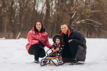happy family with sled walking in winter forest