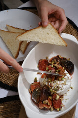 man eating melted brie cheese with figs and pistachios close-up of hands top view