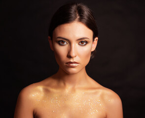 Close-up portrait of young woman with golden makeup. - 662610363