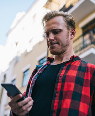 Pensive troubled man interacting with smartphone on street in city
