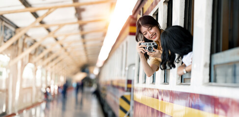 Happy smiling woman taking photo with her friend  from window train, traveling by train - obrazy, fototapety, plakaty