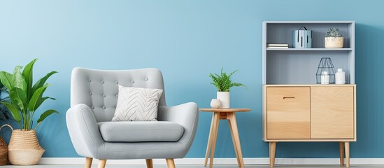 Blue wall with posters in living room interior with wooden cupboard featuring grey armchair and pouf With copyspace for text