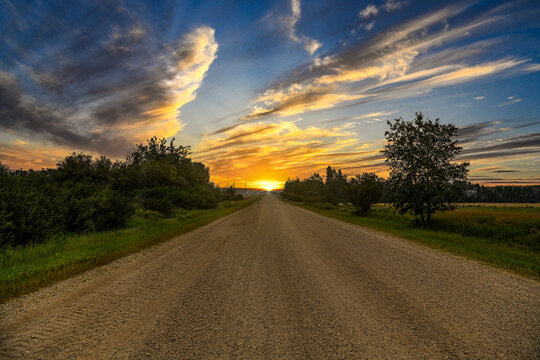 Straight road through rural landscape at sunset, Alberta, Canada