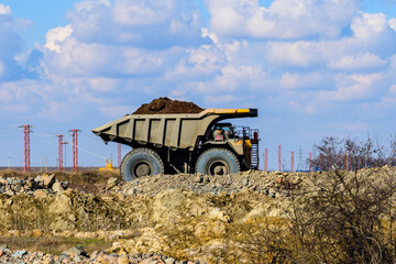 Huge dump truck loaded with iron ore on a gravel road