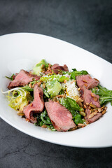 salad with pieces of beef, pistachios, lettuce and cheese side view