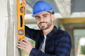 professional worker in helmet is measuring wall with level