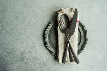 Overhead view of a vintage place setting with a pewter plate and cutlery