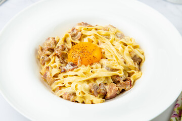 pasta in cream sauce with egg and black pepper on top side view