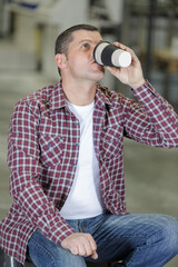 worker drinking coffee and resting sitting in factory