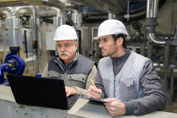 two man worker welding big steel piping in factory