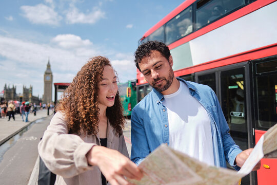 Smiling couple reading map on street in city