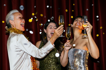 Happy women with champagne glasses enjoying dance at new year party celebration