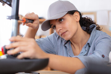 female mechanic using screwdriver to adjust bicycle seat