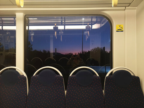 Reflection of a woman taking a photo of an empty metro at sunrise, Florence, Tuscany, Italy