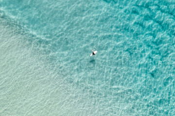 A surfer is seen sitting on his board in the middle of the ocean