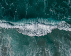 Aerial view of a large wave crashing close to the shore