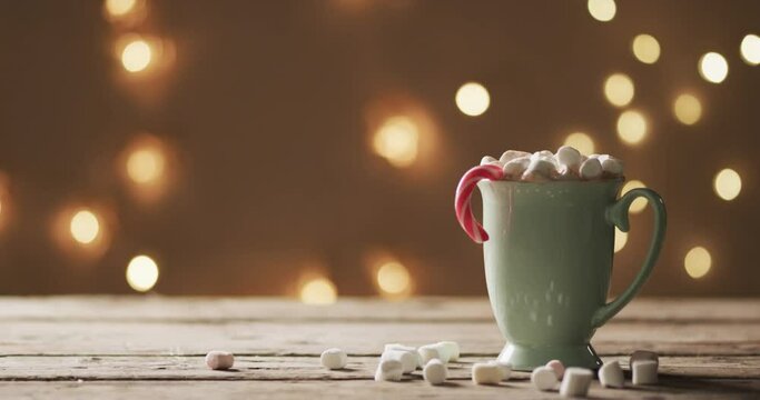 Video of mug of chocolate, marshmallows, christmas decorations and copy space on wooden background