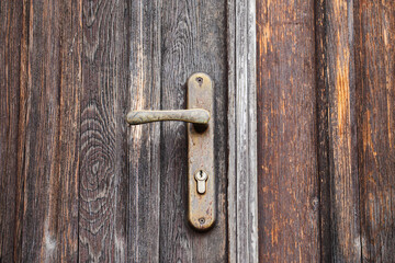 Old wooden door. Closeup rusty door handle. Metal keyhole.