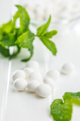 Mint candies. Menthol bonbons and mint leaves on white table.
