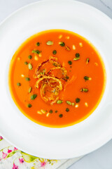 top view of pumpkin cream soup with pieces of meat in a white plate
