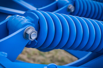 Blue hard spring made of steel. Part of big industrial or agricultural machine