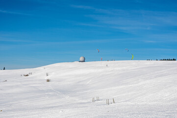 Kite surfing on the Wasserkuppe with Radome in the snow with a blue sky
