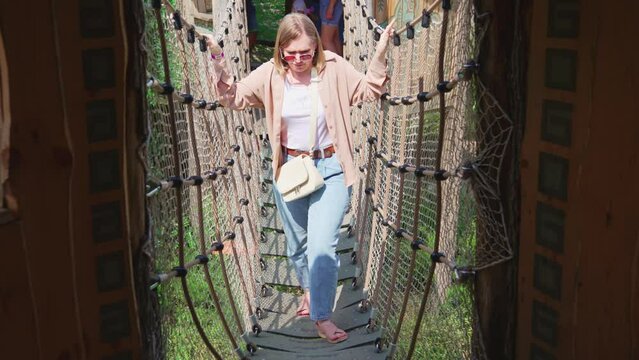 CWoman afraid of heights and walking on a suspension bridge. State-of-the-art play area.